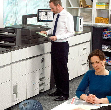 ein mann steht an einem multifunktionsdrucker ein mann steht an einem multifunktionsdrucker